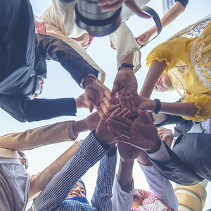 A group of people with their hands in a circle. A group of people with their hands in a circle.