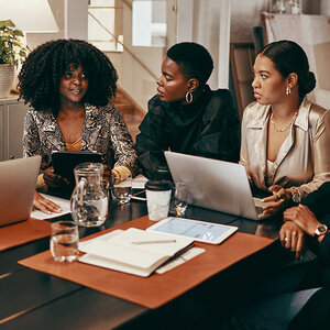 Three South African women sit at a table during a strategy meeting. Three South African women sit at a table during a strategy meeting.