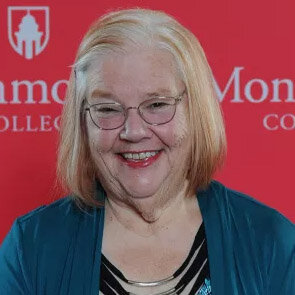 Headshot of Karen Krueger against a red background with Monmouth College logo.