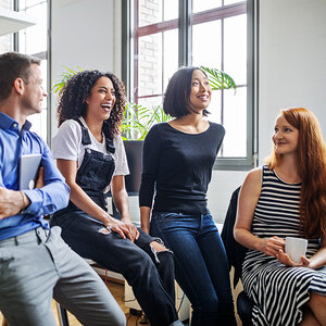A group of co-workers smiling and laughing during an informal meeting. A group of co-workers smiling and laughing during an informal meeting.
