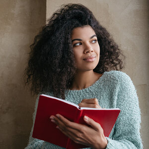 An African American woman writes in her journal. An African American woman writes in her journal.