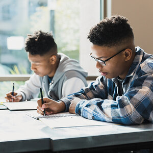Two students taking notes in class.