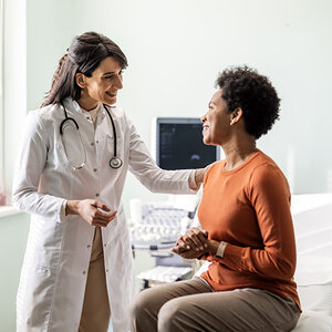 An African American woman smiles during a health screening with her doctor.