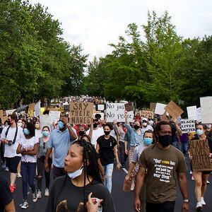 A large multi-racial group of people marching for racial justice. A large multi-racial group of people marching for racial justice.