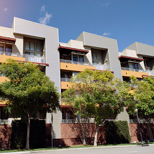A row of modern low-rise apartment buildings surrounded by trees.
