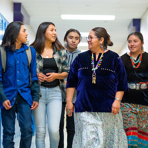A group of indigenous teens talking with their teacher in a school hallway. A group of indigenous teens talking with their teacher in a school hallway.