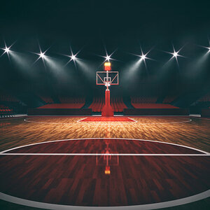 A darkened basketball court with spotlights illuminating one end of the court.