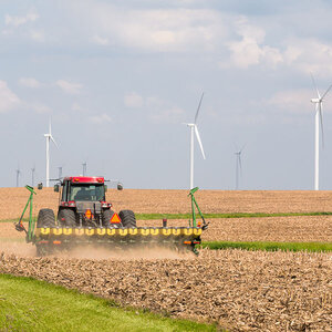 A farmer tilling his corn fields with windmills in the background. A farmer tilling his corn fields with windmills in the background.