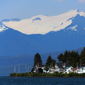 A coastal community in Alaska with snowcapped mountains rising in the background. A coastal community in Alaska with snowcapped mountains rising in the background.