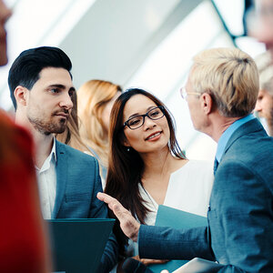Two men and a woman dicsssing an issue as one man uses his hand to emphasize a point.