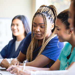 Two African American medical students review their work on a laptop. Two African American medical students review their work on a laptop.