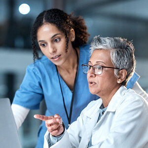 Two female doctors are reviewing test results on a computer screen. Two female doctors are reviewing test results on a computer screen.