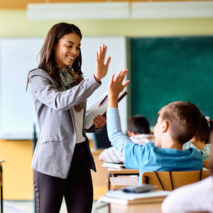 A teacher high-fiving a student in class. A teacher high-fiving a student in class.