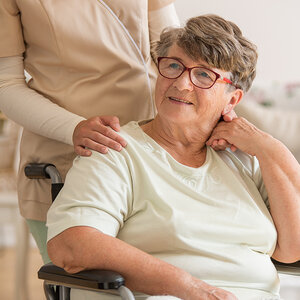 A Parkinson’s patient in a wheelchair is comforted by her caregiver. A Parkinson’s patient in a wheelchair is comforted by her caregiver.