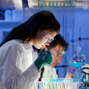 A female scientist works in a lab holding a pipette. A female scientist works in a lab holding a pipette.