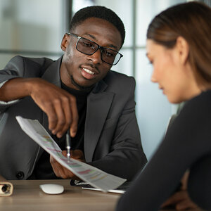 A financial advisor review account records with his female client.