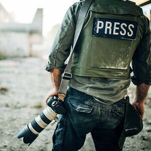 A reporter stands in rumble with a camera. A reporter stands in rumble with a camera.