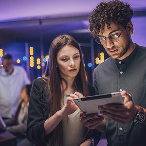Two data engineers working on a tablet. Two data engineers working on a tablet.