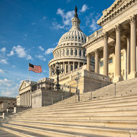 The exterior of the Capitol in Washington, D.C. with an American flag flying under a bright blue sky. The exterior of the Capitol in Washington, D.C. with an American flag flying under a bright blue sky.