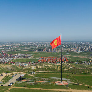 Aerial view of Bishkek city from the mountains. Flagpole with Kyrgyzstan flag. Aerial view of Bishkek city from the mountains. Flagpole with Kyrgyzstan flag.