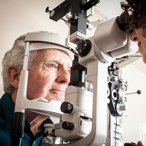 An older man is given an eye exam by a female ophthalmologist. An older man is given an eye exam by a female ophthalmologist.
