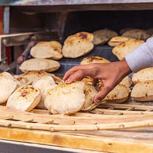Pita bread being removed from a baker’s oven. Pita bread being removed from a baker’s oven.