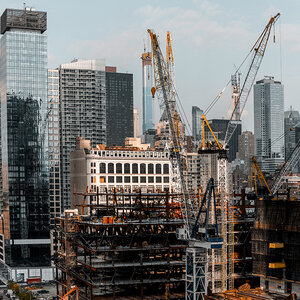 A city landscape with a building under construction surrounded by cranes. A city landscape with a building under construction surrounded by cranes.