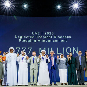 People in business attire and traditional Arab dress holding hands on a stage.