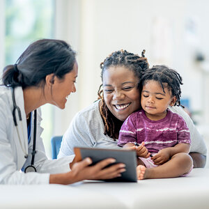 A female doctor shares the results of an exam with a mother holding her baby.