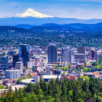 A view of a city in a green valley with a snowcapped mountain in the background—Portland, Oregon…. A view of a city in a green valley with a snowcapped mountain in the background—Portland, Oregon….