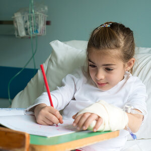 A young girl in a hospital bed draws in a coloring book. A young girl in a hospital bed draws in a coloring book.