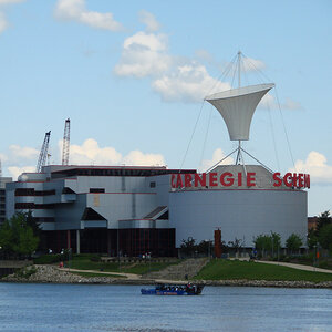 A modern museum building on a riverfront with a sign on top that reads: Carnegie Science Center. A modern museum building on a riverfront with a sign on top that reads: Carnegie Science Center.