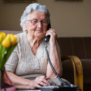 An older woman answers the telephone.