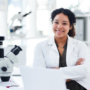 A young female scientist in a lab coat crosses her arms and poses for a photo. A young female scientist in a lab coat crosses her arms and poses for a photo.