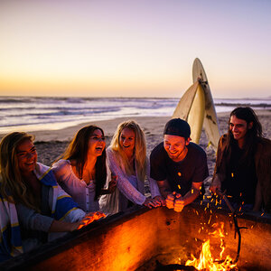 Young people sitting by a fire on the beach. Young people sitting by a fire on the beach.