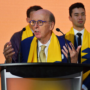 A bald man with glasses stands at a podium giving a speech – Stephen J.R. Smith.