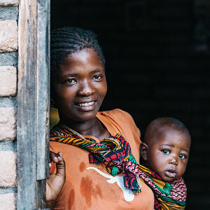 A mother holding her baby in a doorway.