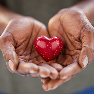 A small heart is held in a woman’s hands symbolizing the idea of giving. A small heart is held in a woman’s hands symbolizing the idea of giving.