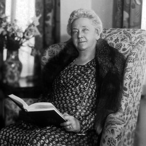 "A black and white image of an older woman sitting in a chair reading a book - a photo of Kate Bidding Reynolds." "A black and white image of an older woman sitting in a chair reading a book - a photo of Kate Bidding Reynolds."