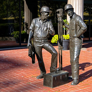 A bronze sculpture of two construction workers stands in a public plaza - The Builders by George Danhires. A bronze sculpture of two construction workers stands in a public plaza - The Builders by George Danhires.