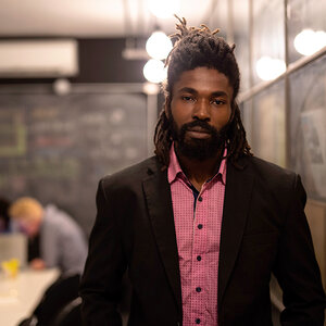 An Black businessman wearing a red shirt and black suit jacket looking at the camera. An Black businessman wearing a red shirt and black suit jacket looking at the camera.