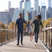 A family walking along a footbridge with the skyscrapers behind them. A family walking along a footbridge with the skyscrapers behind them.