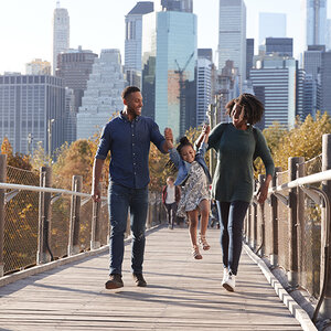 A family walking along a footbridge with the skyscrapers behind them.