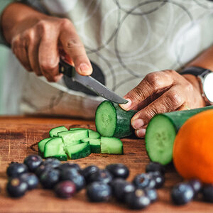 A close up image of a man chopping vegetables.