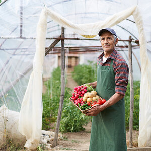 A farmer holding a basket of vegetables. A farmer holding a basket of vegetables.