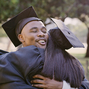 Two graduates hugging on commencement day. Two graduates hugging on commencement day.
