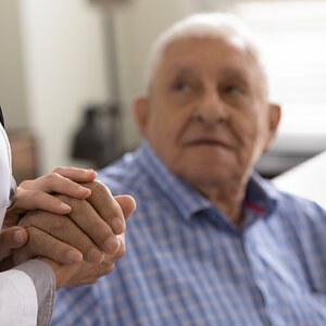 An older patient holding the hand of a caregiver. An older patient holding the hand of a caregiver.