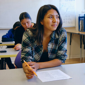 An Indigenous high school student sits at her classroom desk.