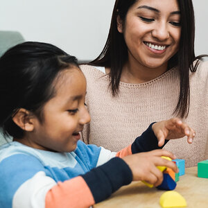 An Indigenous woman and child play with colored learning blocks. An Indigenous woman and child play with colored learning blocks.