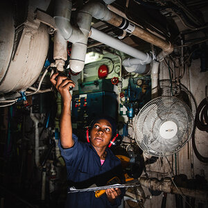 A female maritime cadet working in a ship's engine room.